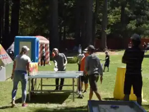 People playing table tennis at an outdoor event on a grassy lawn