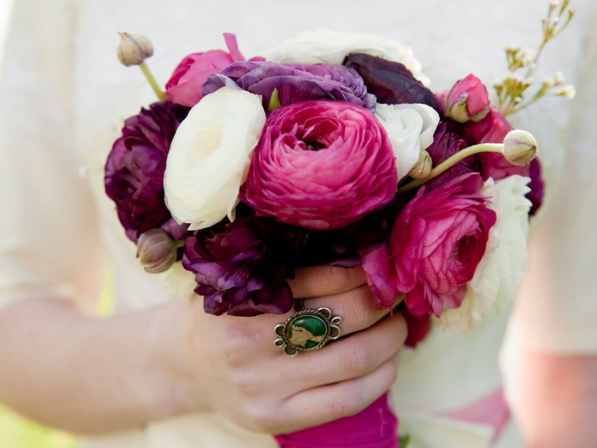 White, pink, and wine ranunculus bouquet held by bride
