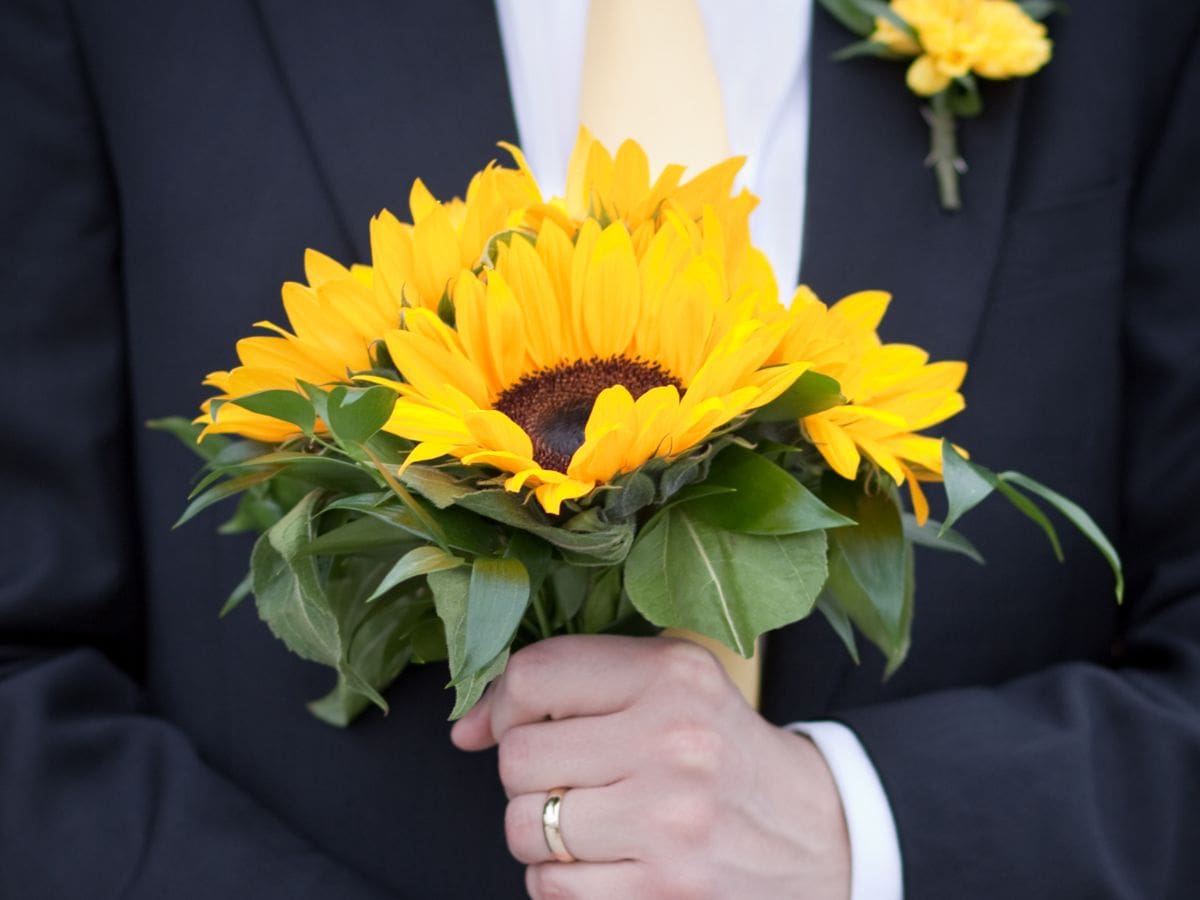 Groom holding a sunflower bouquet on his wedding day