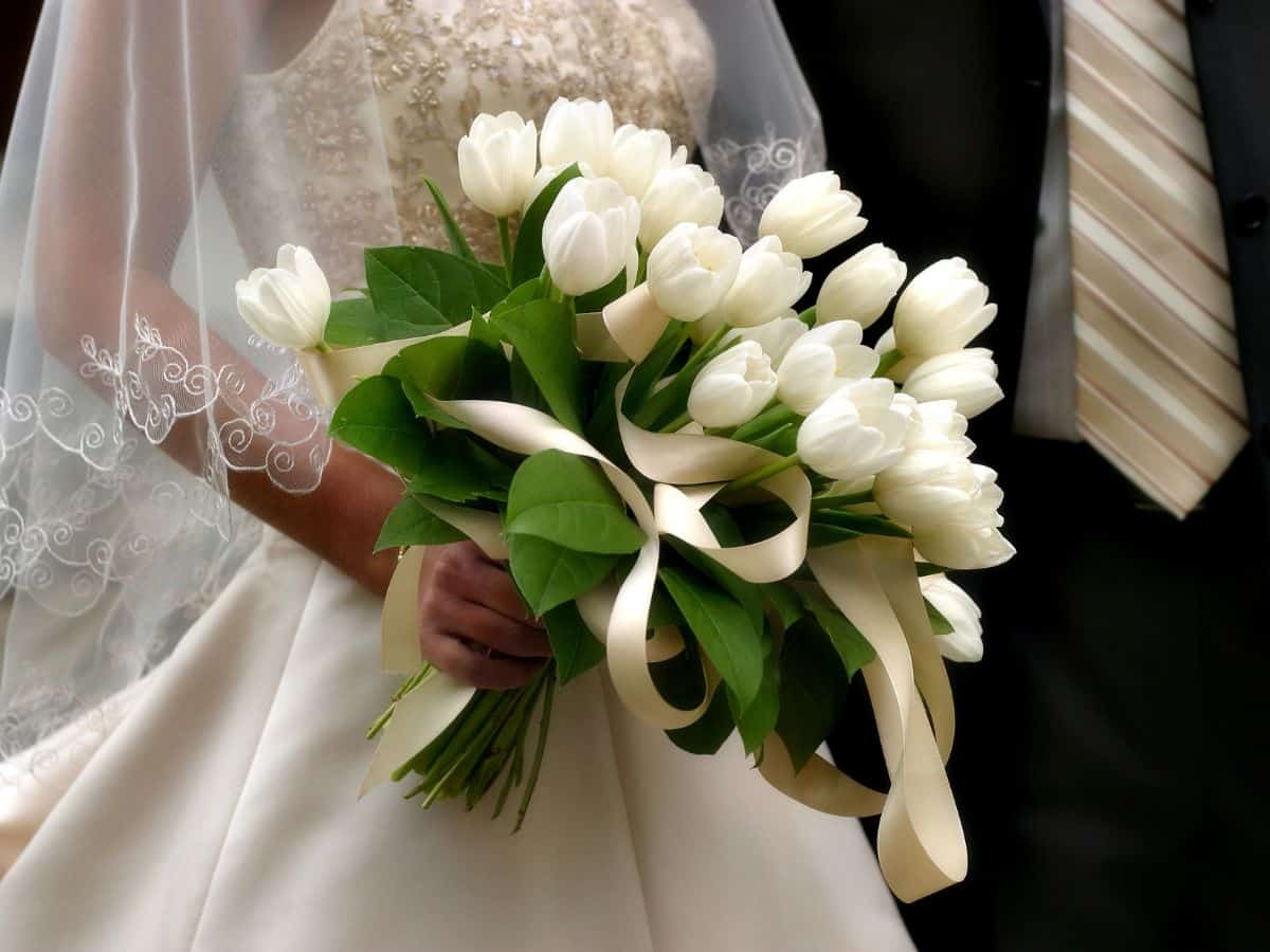 Close-up of a bride holding white tulips bouquet