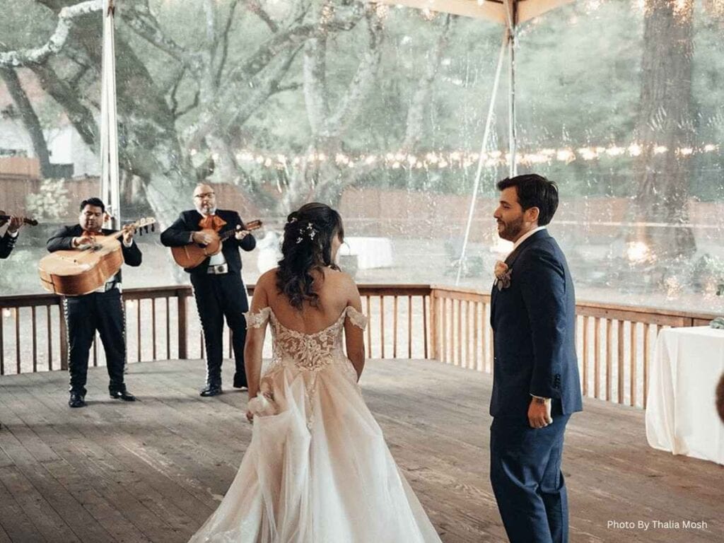 Bride and groom watch a mariachi band play on a wooden deck outdoors