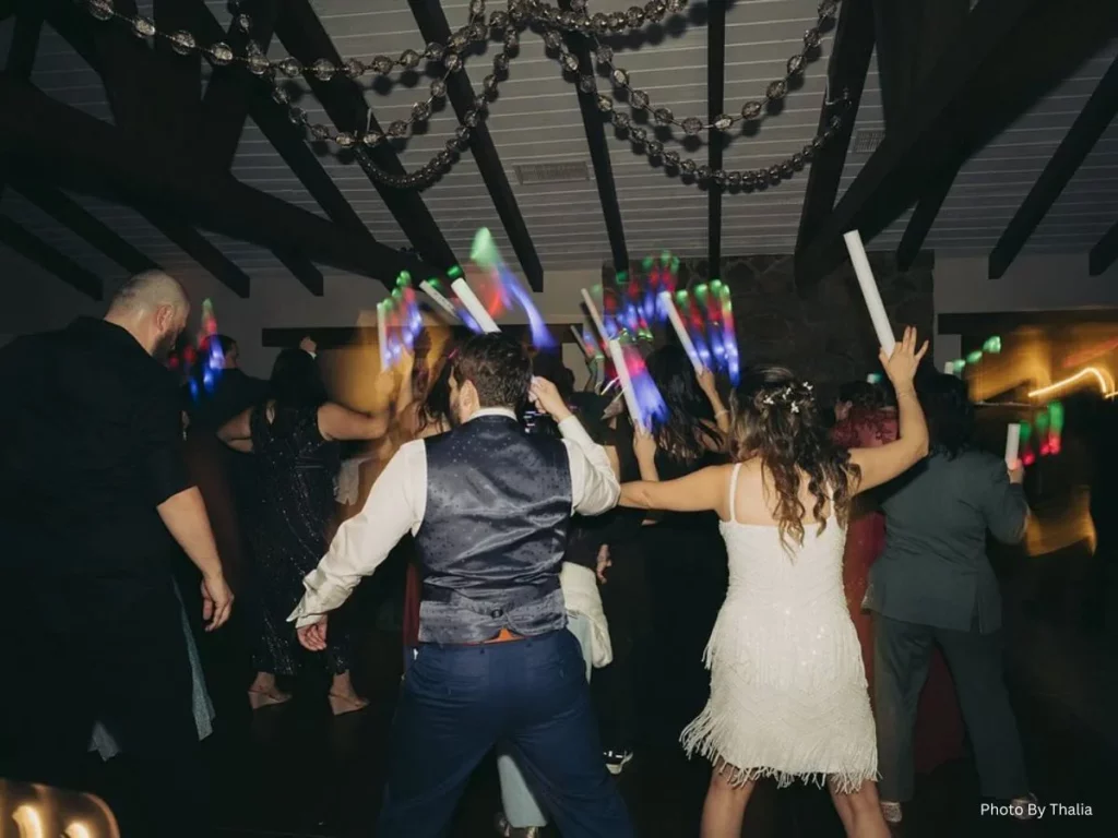 Wedding guests dancing with glow sticks at reception